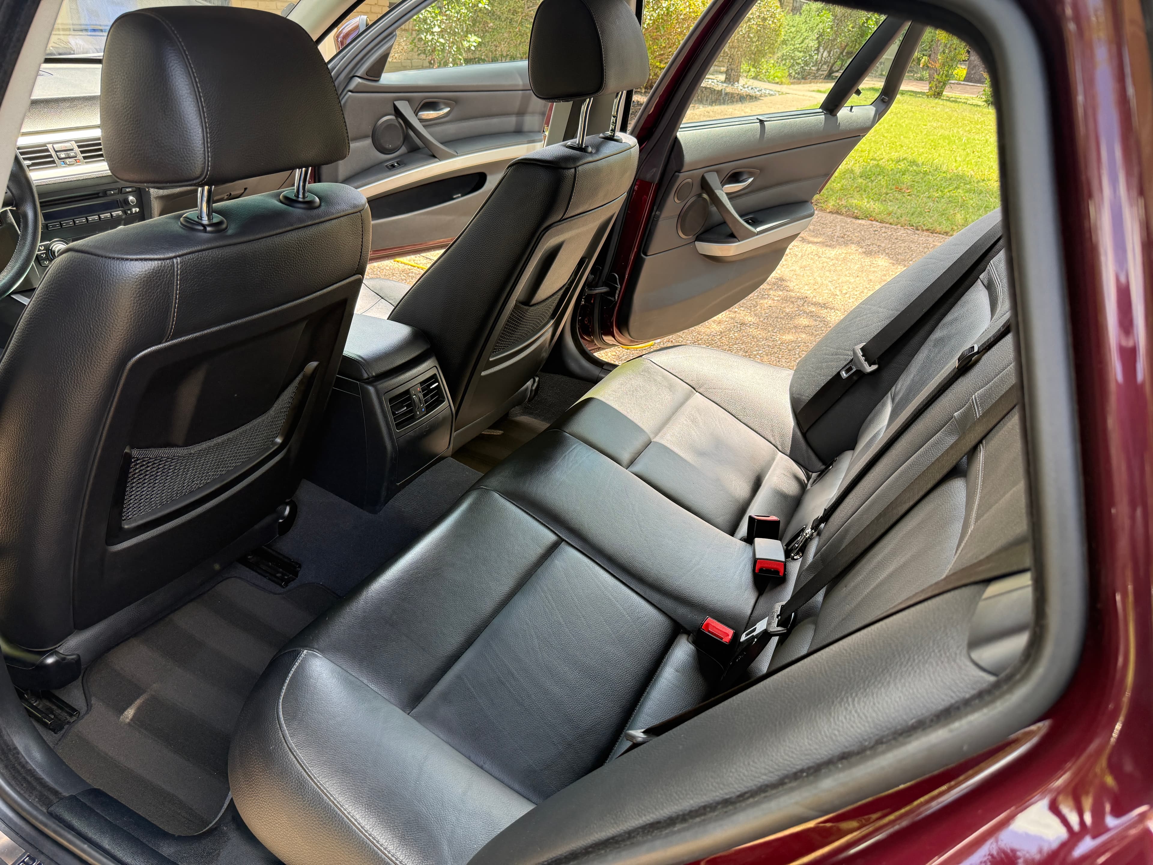 Interior of a car featuring black leather rear seats and an open passenger door.